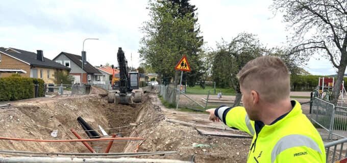 Medarbetare klädd i varselkläder pekar in mot arbetsområde med diken och grävmaskiner.