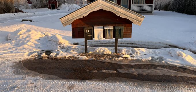 Vatten rinner längs en väg i ett vintrigt landskap.